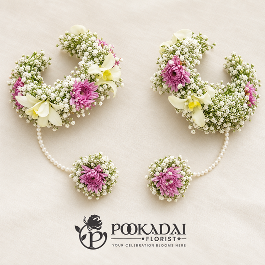 Pair of white and mauve floral haath phool with baby’s breath wrist bands connected to matching floral rings by white bead strands.